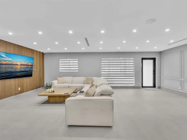 Room featuring an accent wall with vertical wood slat paneling, recessed lighting, large-format tile flooring, layered window treatments, and wainscoting