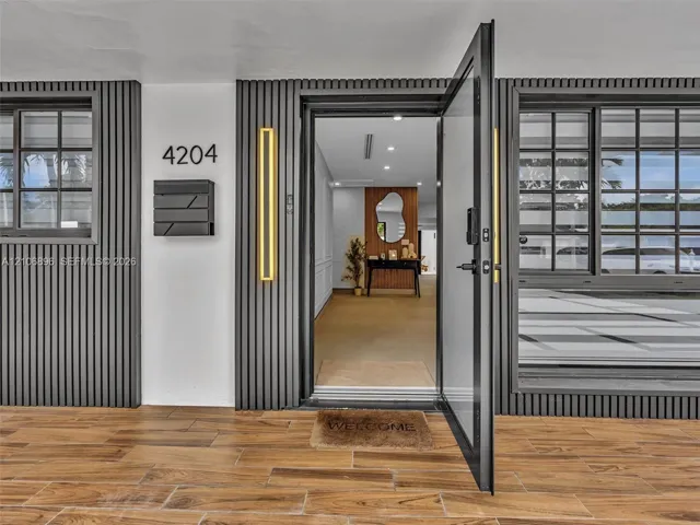 Entryway featuring dark vertical slatted exterior siding, wood-finish tile flooring, matte black grid-pane windows, and dual vertical wall-mounted sconces