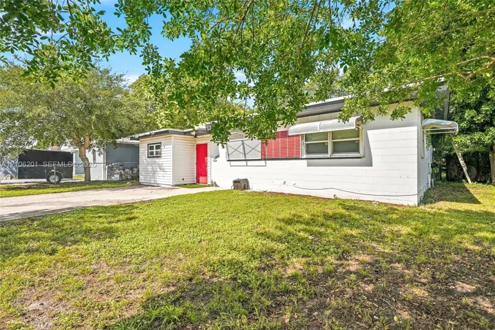 Single-story residence featuring a white horizontal siding exterior, concrete driveway, and metal window awnings