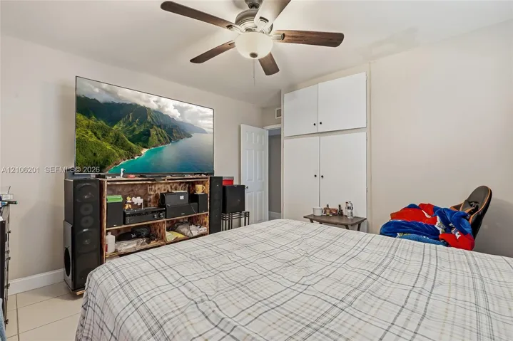 Room featuring a ceiling fan with integrated lighting and built-in floor-to-ceiling cabinetry with overhead storage
