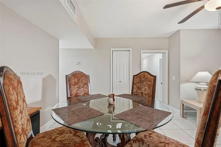Neutral interior featuring white tile flooring, six-panel interior doors, and a ceiling-mounted fan with integrated light fixture