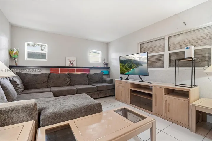 Living area featuring neutral wall paint, tile flooring, and multiple horizontal windows