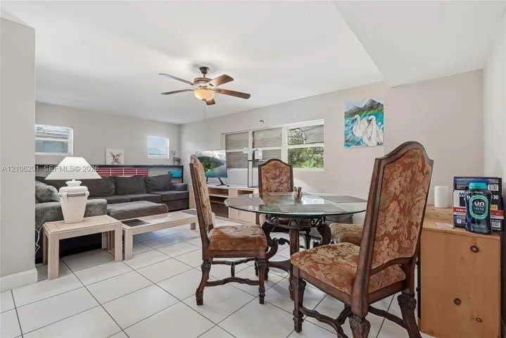 Open-concept interior featuring neutral wall tones, large-format tile flooring, and a ceiling fan with integrated light fixture
