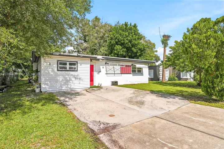 Single-story residence featuring white horizontal siding, a bright red front door, and a concrete driveway