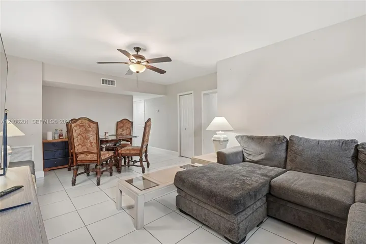 Interior space featuring neutral wall tones, large-format ceramic tile flooring, and a ceiling-mounted fan with integrated lighting