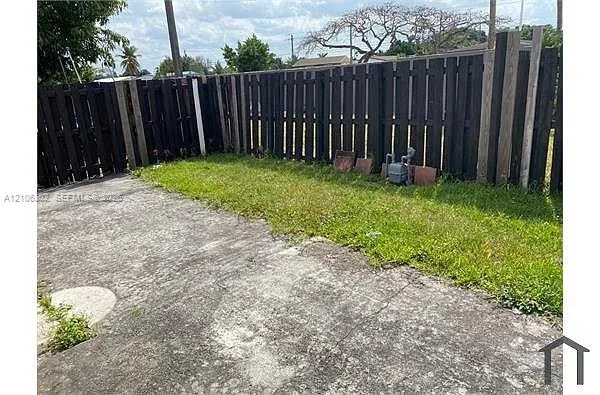 Fenced outdoor space featuring a concrete patio and lawn area
