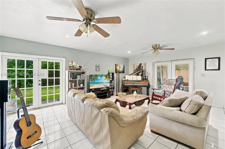 Spacious interior featuring white ceramic tile flooring, dual ceiling fans, and two sets of double-paned French doors