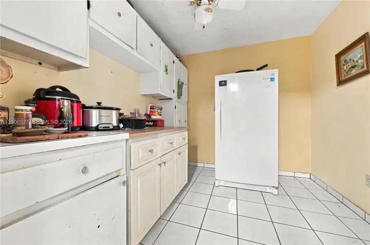 Kitchen featuring white raised-panel cabinetry, ceramic tile flooring, and a ceiling-mounted light fixture