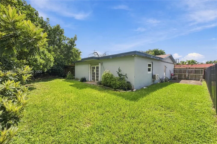 Expansive backyard featuring a large grass lawn, mature trees, and perimeter fencing