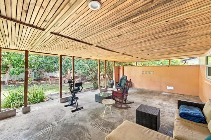 Covered patio featuring a wood-slat ceiling, recessed lighting, concrete flooring, and structural support posts