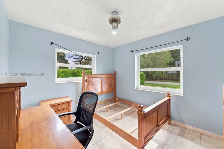 Room featuring tile flooring, neutral wall paint, and dual windows with built-in curtain rods