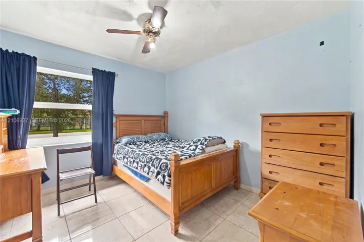 Room featuring large-format tile flooring, a multi-pane window, and a ceiling fan with integrated lighting