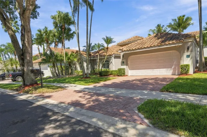 Stucco exterior featuring a multi-hipped tile roof, attached two-car garage, and a decorative paver​​‌​​​​‌​​‌‌​‌‌​​​‌‌​‌​‌​‌​​​‌​​ driveway