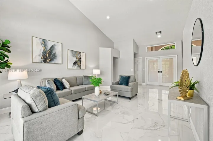 Vaulted ceilings, large-format polished tile flooring, double-entry front doors, and transom windows