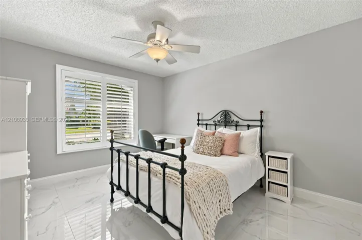 Polished stone-look flooring, white plantation shutters, and a central ceiling fan with an integrated light fixture