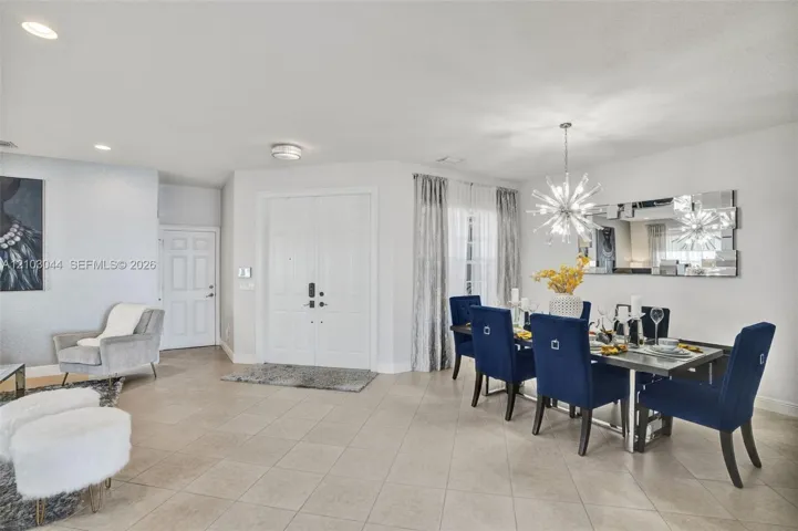 Open-concept space featuring neutral large-format tile flooring, recessed ceiling lighting, a contemporary multi-point starburst chandelier, and double-door entry