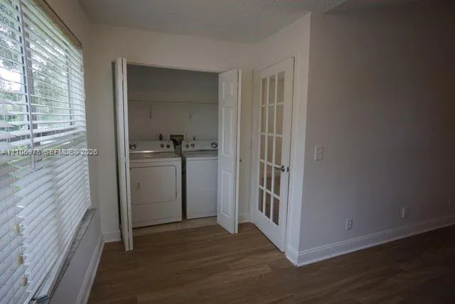 Laundry closet with bi-fold doors, wood-finish flooring, and a multi-pane glass door