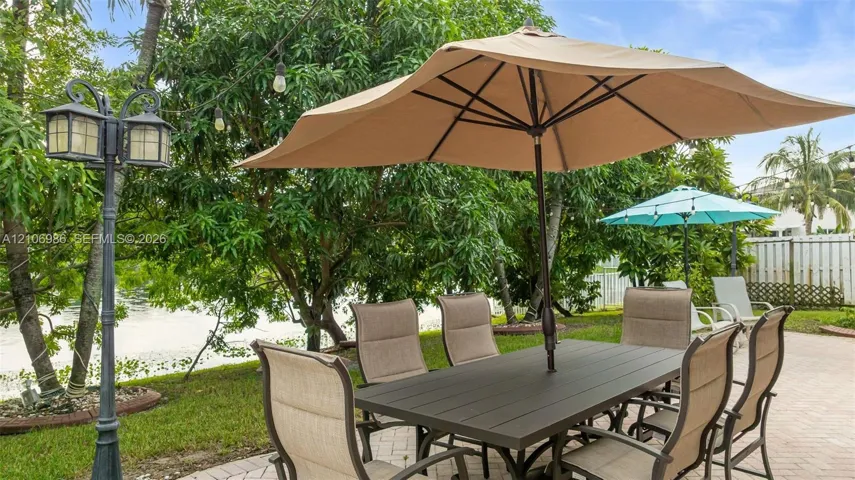 Paver patio featuring a decorative metal lamp post and mature perimeter landscaping