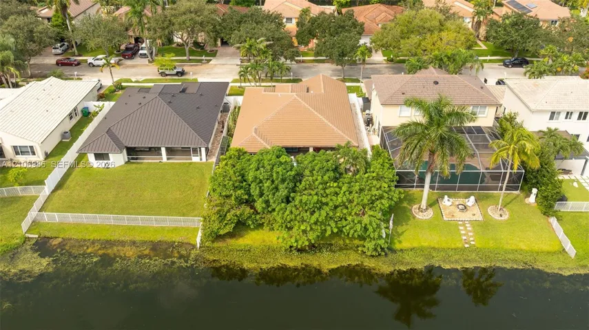 Waterfront residential lot featuring a manicured lawn, established landscaping, and perimeter fencing