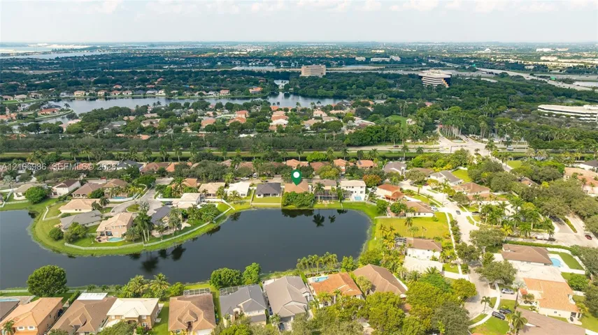 Aerial perspective of residential property featuring waterfront positioning, tile roof construction, and established perimeter vegetation