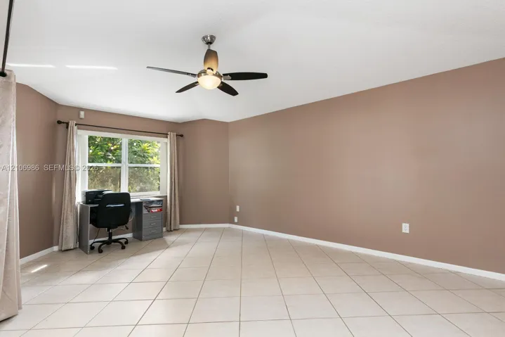 Room featuring large-format diagonal tile flooring, neutral wall paint, and a ceiling-mounted fan with integrated lighting