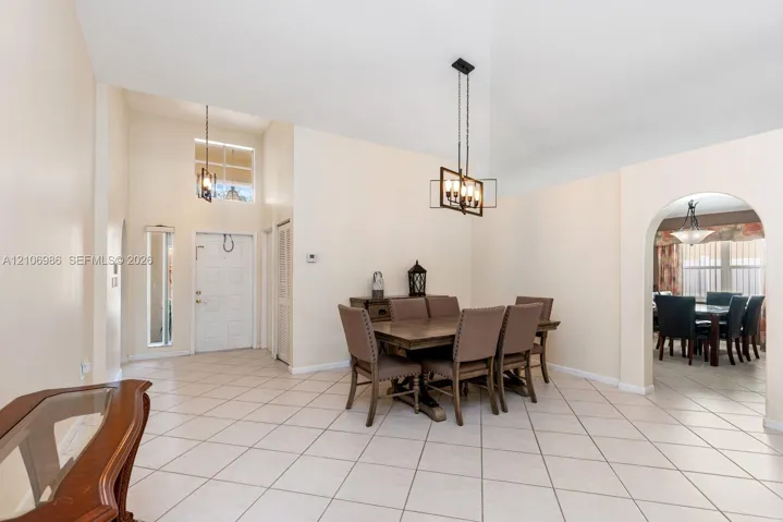 Vaulted ceilings, large-format tile flooring, a geometric metal chandelier, and a prominent arched entryway