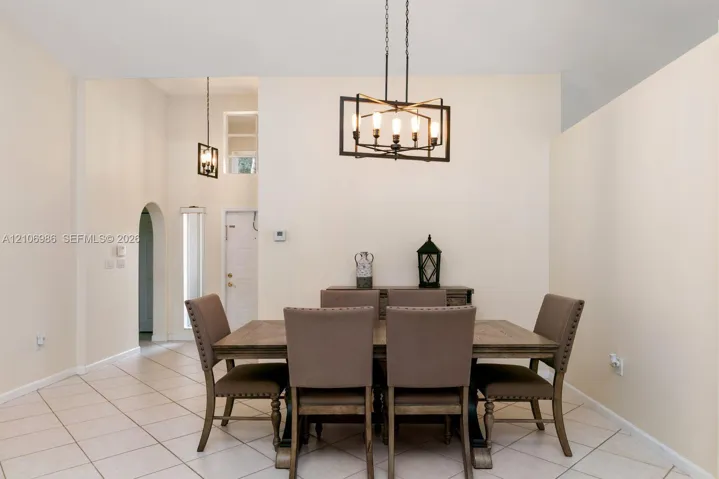 Vaulted ceilings featuring geometric metal chandeliers, ceramic tile flooring, and an arched entryway