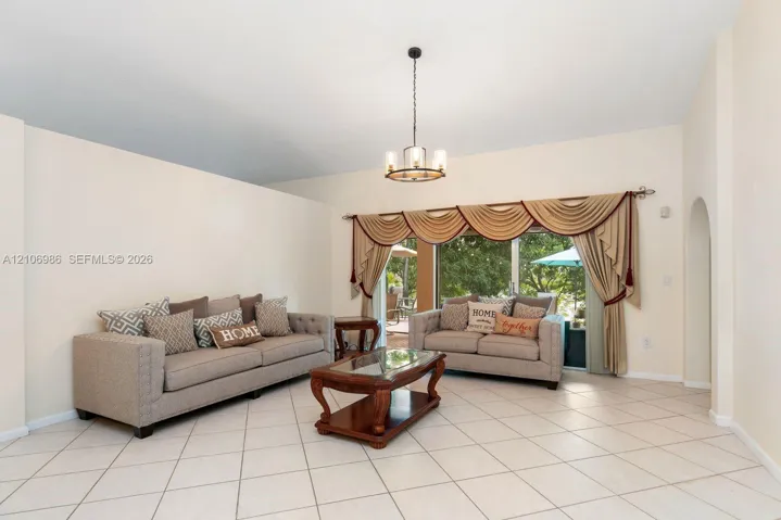 Living area featuring high ceilings, neutral wall tones, diagonal-set ceramic tile flooring, a multi-arm metal chandelier, and a sliding glass door
