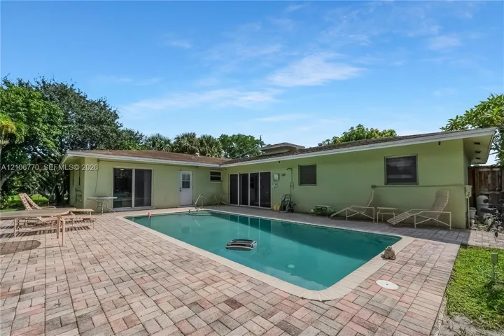 In-ground swimming pool with a concrete surround, paver patio, and sliding glass door access