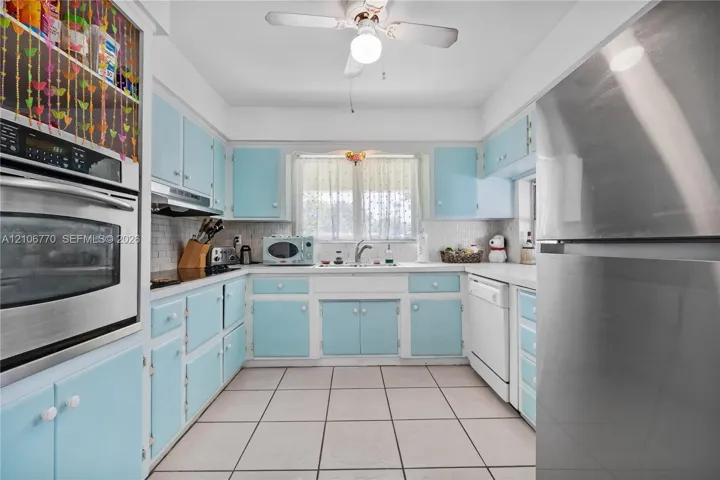 Kitchen featuring custom cabinetry, stainless steel oven, stainless steel refrigerator, white tiled backsplash, and ceramic tile flooring