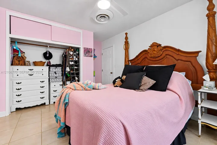 Bedroom featuring tile flooring, sliding door closet with integrated upper storage cabinets, and a central ceiling light fixture