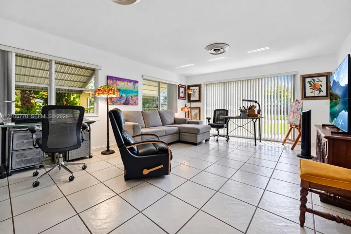 Neutral ceramic tile flooring, large-format windows, and sliding glass doors featuring vertical blinds