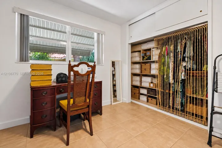 Neutral-toned tile flooring, horizontal sliding window, and built-in closet featuring upper storage cabinetry and partitioned shelving