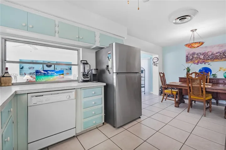 Kitchen featuring custom cabinetry, stainless steel refrigerator, white dishwasher, and tile flooring