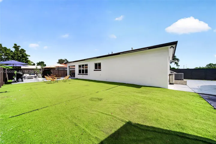 Spacious backyard featuring artificial turf, a paved concrete patio, and opaque privacy fencing