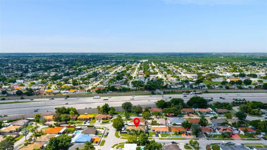 Aerial perspective of a suburban neighborhood featuring a residential lot with mature landscaping and a low-pitched roofline