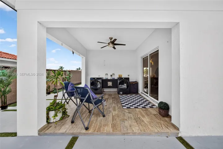 Covered patio featuring wood-finish flooring, a ceiling fan, and sliding glass door access