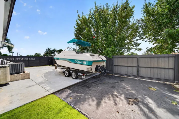 Concrete patio area enclosed by dark-toned privacy fencing featuring a wide dual-swing gate