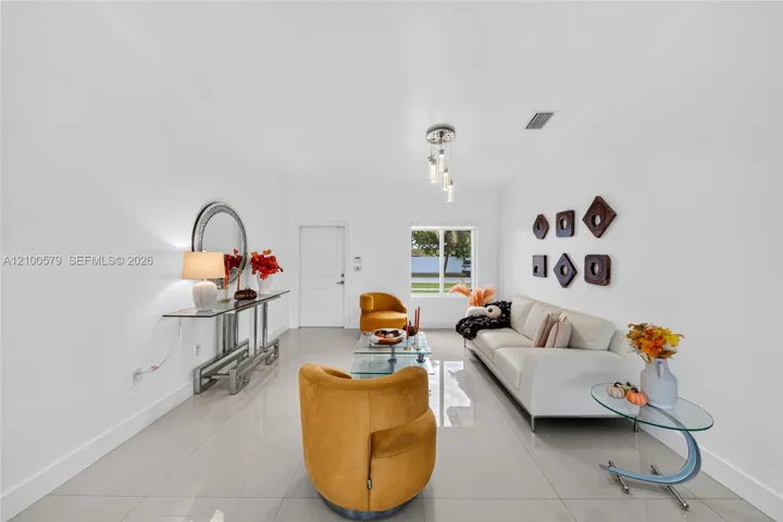 Open-concept living space featuring high-gloss tile flooring, multi-light pendant fixture, and natural light via window and exterior door