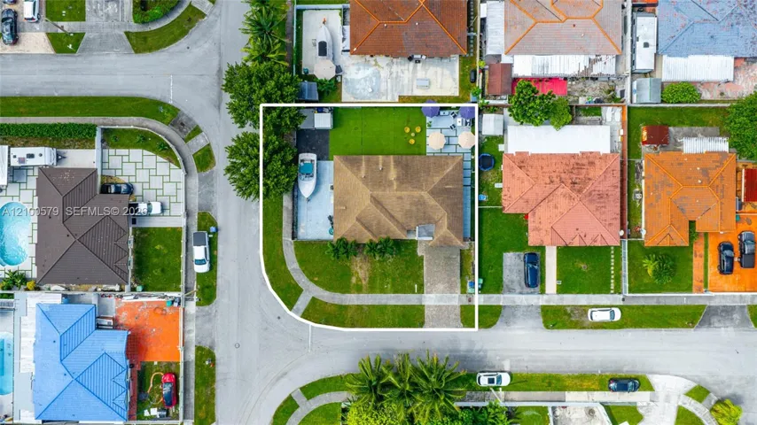 Corner lot residence featuring a paver driveway, side-access parking, a spacious lawn, and a rear hardscaped patio