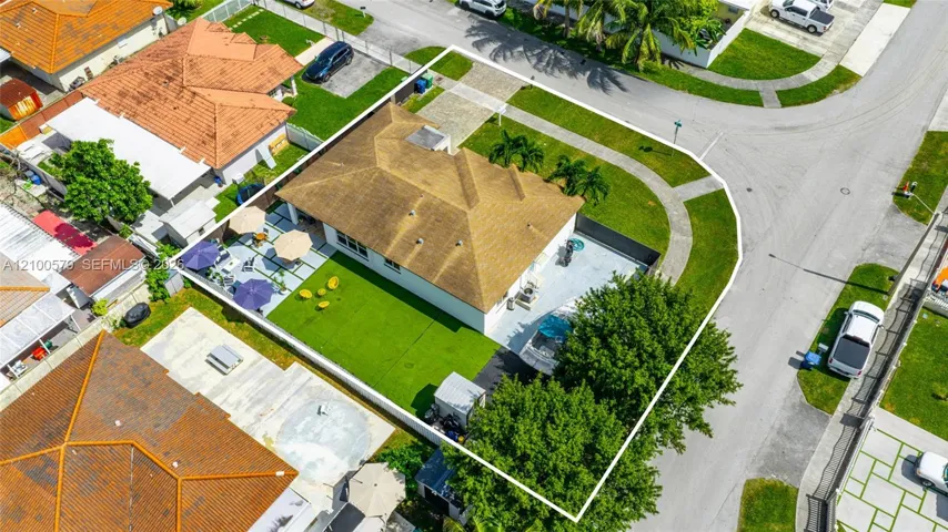 Corner lot property featuring a hip roof, paved driveway, expansive lawn, and fenced rear perimeter