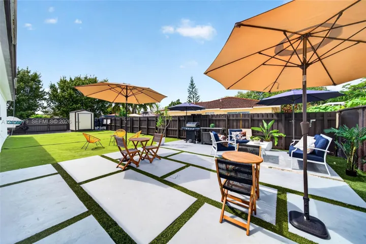 Rear exterior area featuring a concrete paver patio with turf inlays and a full-perimeter privacy fence