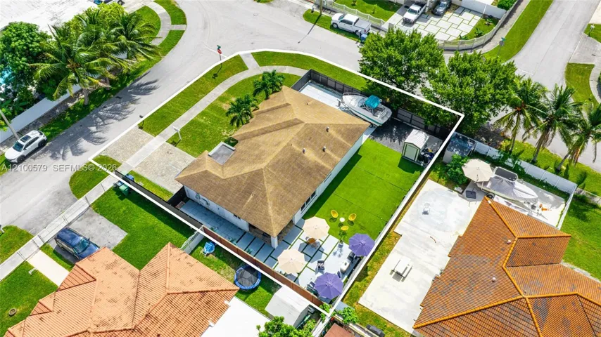 Corner lot featuring a fenced backyard, concrete paver patio, lush lawn, and side-yard boat storage area