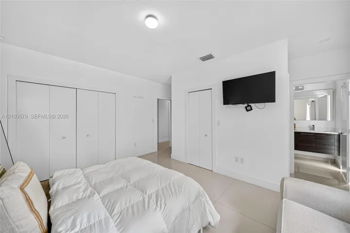 Interior space featuring large-format tile flooring, dual reach-in closets with bi-fold doors, and a neutral white color palette