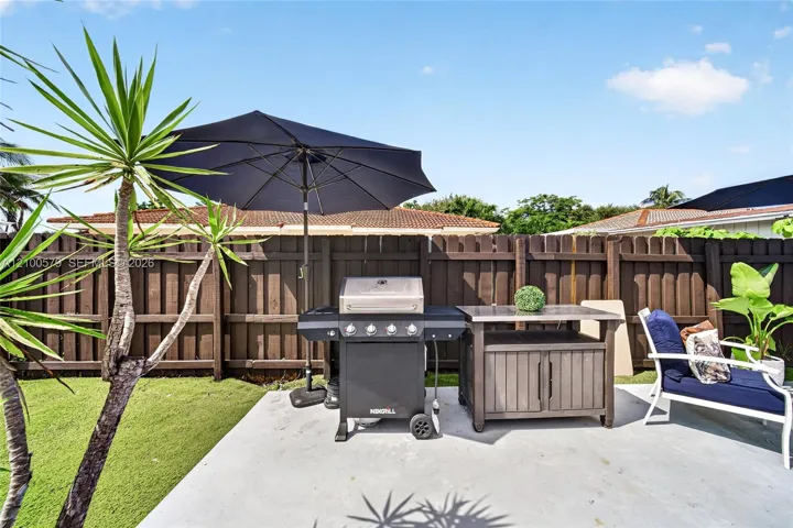 Outdoor patio featuring a poured concrete floor and a privacy wood fence