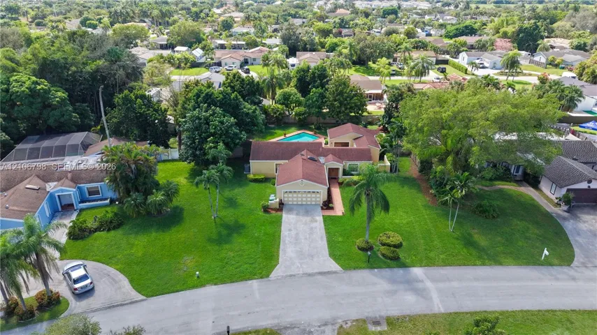 Aerial perspective featuring a multi-gabled roofline, concrete driveway, attached garage, in-ground swimming pool, and manicured lawn