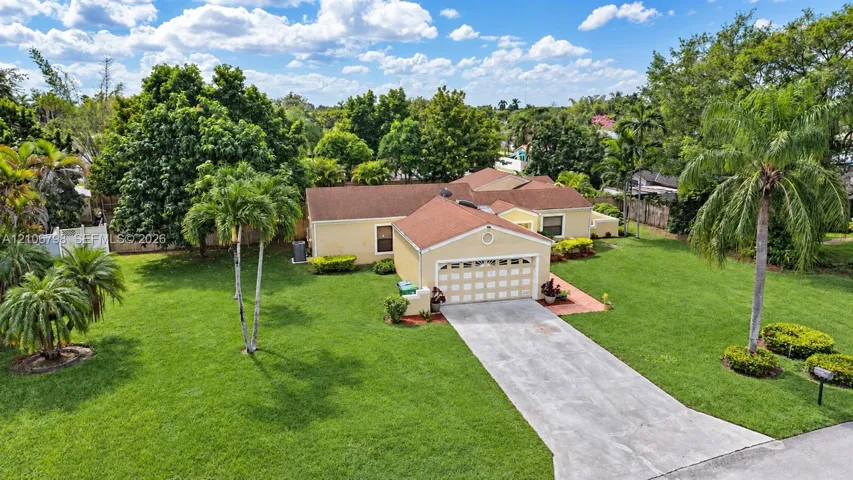 Single-story residence featuring a multi-gabled shingle roof, two-car garage, concrete driveway, and expansive lawn with mature landscaping