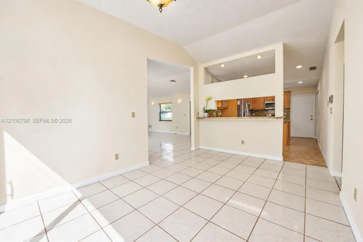 Ceramic tile flooring throughout with vaulted ceilings, recessed lighting, and a breakfast bar pass-through