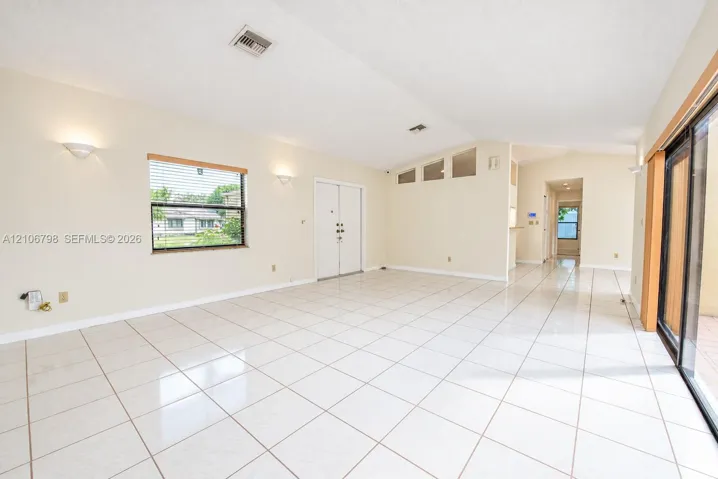 Vaulted ceilings, large-format tile flooring, dual glass-paneled entry doors, transom windows, and sliding glass patio doors