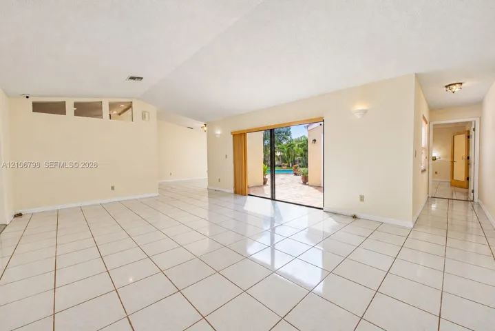 Open-concept interior featuring high ceilings, white tile flooring, recessed wall sconces, clerestory windows, and sliding glass doors